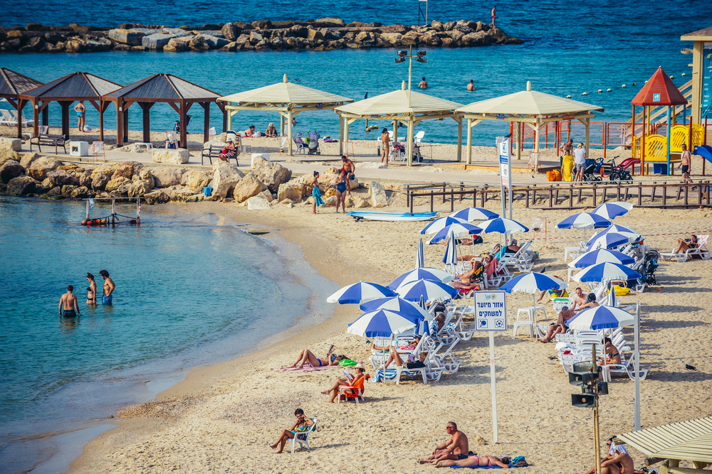 People sunbathe on the beach next to the Hilton Hotel in Tel Aviv