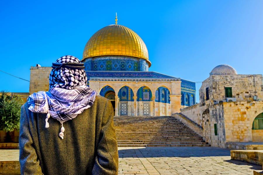 The pensive Palestinian in keffiyeh stands in shade of the Chain Gates, and look at the Dome of the Rock, Jerusalem, Israel.